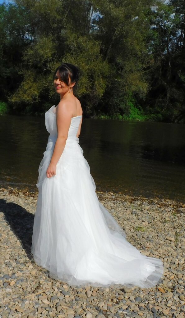 Les Précieuses- Robe de mariée Angelite vue de profil. Bustier recouvert de tulle et tulle pailleté. Bas avec épaisseurs de tulle et un drapé de tulle pailleté.