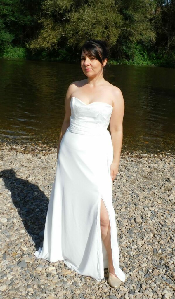 La robe de mariée Ambre est légère et fluide. Son bustier est recouvert de dentelle en tulle brodé.Un drapé en mousseline souligne la taille. Le bas de robe est en mousseline et crêpe 100% polyester et fendue sur le côté gauche. Vue de face