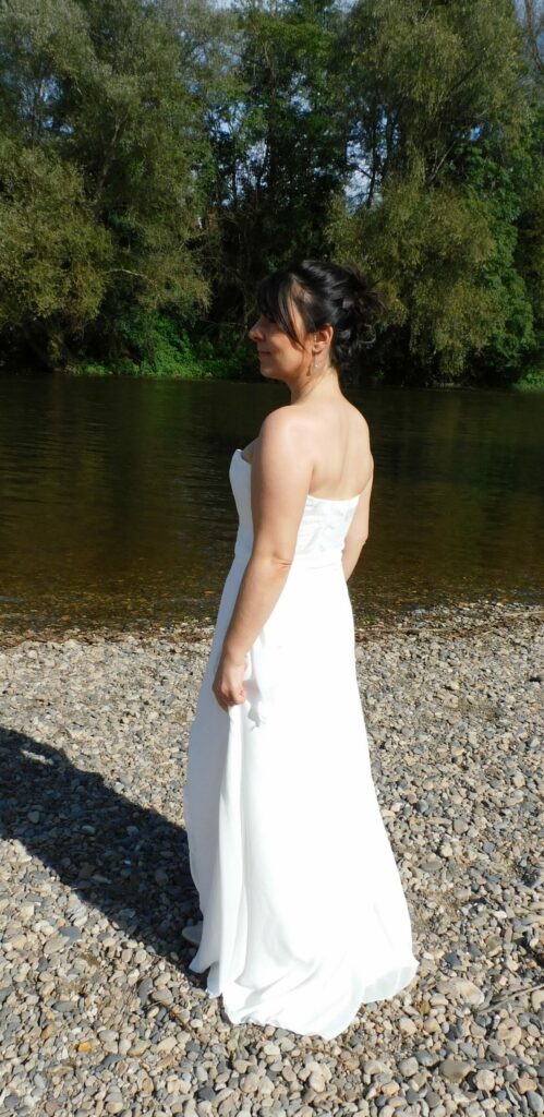 Découvrez la robe de mariée Ambre. Une robe légère et fluide en crêpe. Dentelle en tulle brodé sur le bustier et drapé de mousseline. Vue 3/4 dos