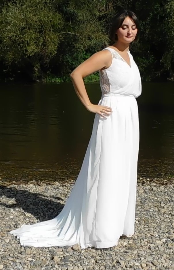 Les Précieuses- Robe de mariée Galène vue de 3/ face. Haut asymétrique en dentelle et mousseline drapée sur l'épaule gauche. Une ceinture recouverte de dentelle met en valeur la taille de la mariée.