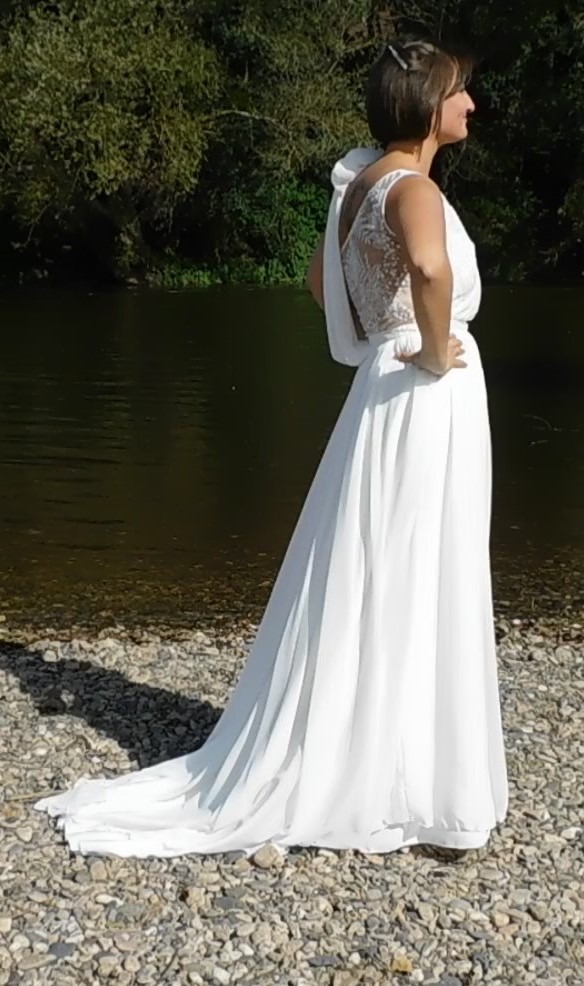 Les Précieuses- Robe de mariée Galène vue de profil. Haut asymétrique en dentelle et mousseline drapée sur l'épaule gauche. Une ceinture recouverte de dentelle met en valeur la taille de la mariée.