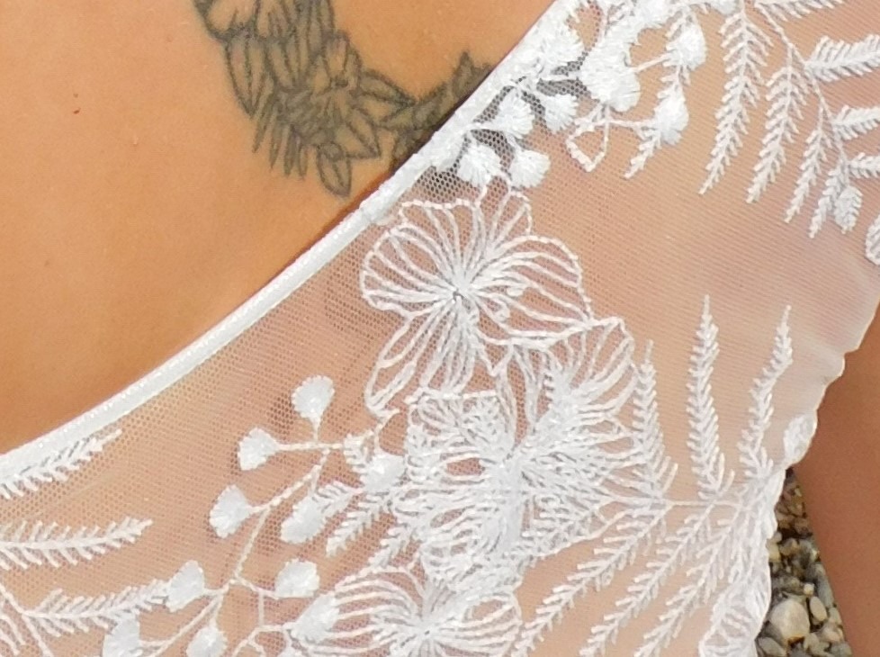 Les Précieuses- Robe de mariée Galène détail. Haut asymétrique en dentelle et mousseline drapée sur l'épaule gauche. Une ceinture recouverte de dentelle met en valeur la taille de la mariée.