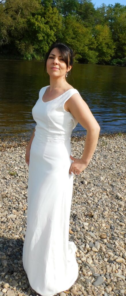 Les Précieuses - Robe de mariée Opale vue de 3/4 face. épouse la silhouette avec sa forme prêt du corps et son col bénitier. La taille est relevée d'un galon de dentelle.