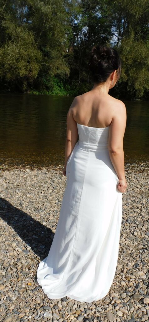 Découvrez la robe de mariée Ambre. Une robe légère et fluide en crêpe. Dentelle en tulle brodé sur le bustier et drapé de mousseline. Vue de dos