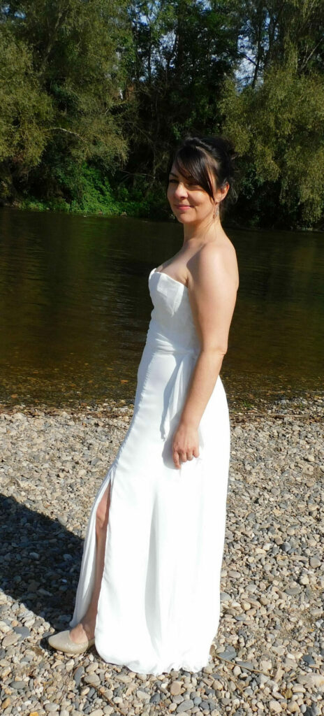 Découvrez la robe de mariée Ambre. Une robe légère et fluide en crêpe. Dentelle en tulle brodé sur le bustier et drapé de mousseline. Vue de profil