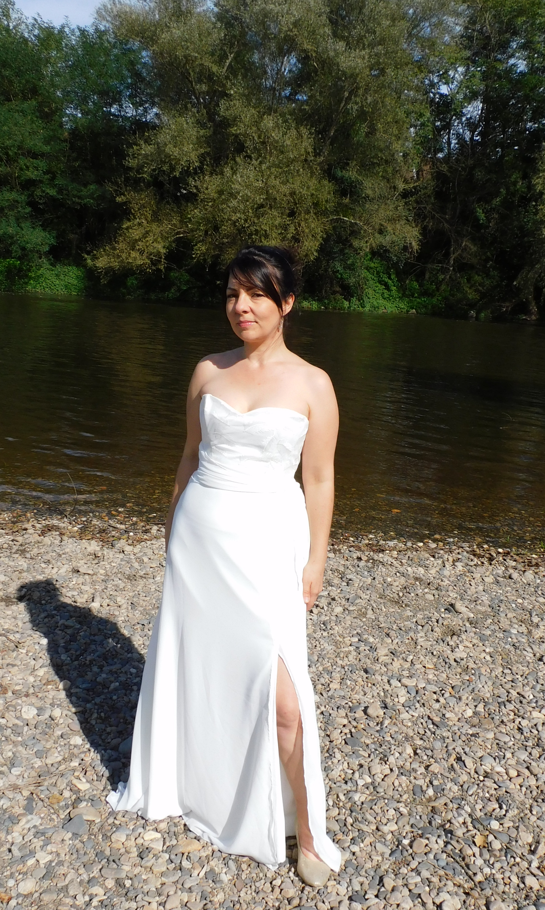La robe de mariée Ambre est légère et fluide. Son bustier est recouvert de dentelle en tulle brodé.Un drapé en mousseline souligne la taille. Le bas de robe est en mousseline et crêpe 100% polyester et fendue sur le côté gauche. Vue de face