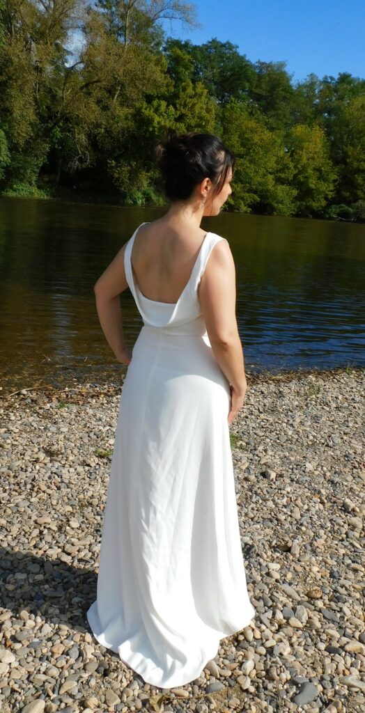 Les Précieuses - Robe de mariée Opale vue de 3/4 dos. épouse la silhouette avec sa forme prêt du corps et son col bénitier. La taille est relevée d'un galon de dentelle.